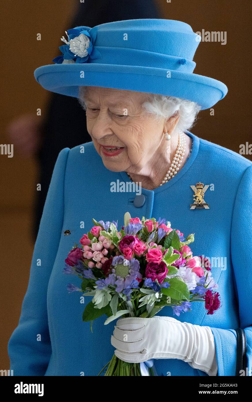 Une abeille atterrit sur les fleurs détenues par la reine Elizabeth II, alors qu'elle rencontra des bénévoles locaux et des travailleurs clés pour les remercier de leurs efforts durant la pandémie, dans la cour du palais de Holyroodhouse à Édimbourg, dans le cadre de son voyage traditionnel en Écosse pour la semaine de Holyrood. Date de la photo: Lundi 28 juin 2021. Banque D'Images