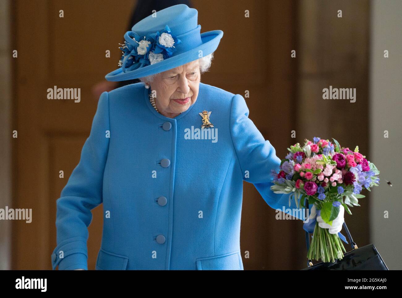 Une abeille atterrit sur les fleurs détenues par la reine Elizabeth II, alors qu'elle rencontra des bénévoles locaux et des travailleurs clés pour les remercier de leurs efforts durant la pandémie, dans la cour du palais de Holyroodhouse à Édimbourg, dans le cadre de son voyage traditionnel en Écosse pour la semaine de Holyrood. Date de la photo: Lundi 28 juin 2021. Banque D'Images