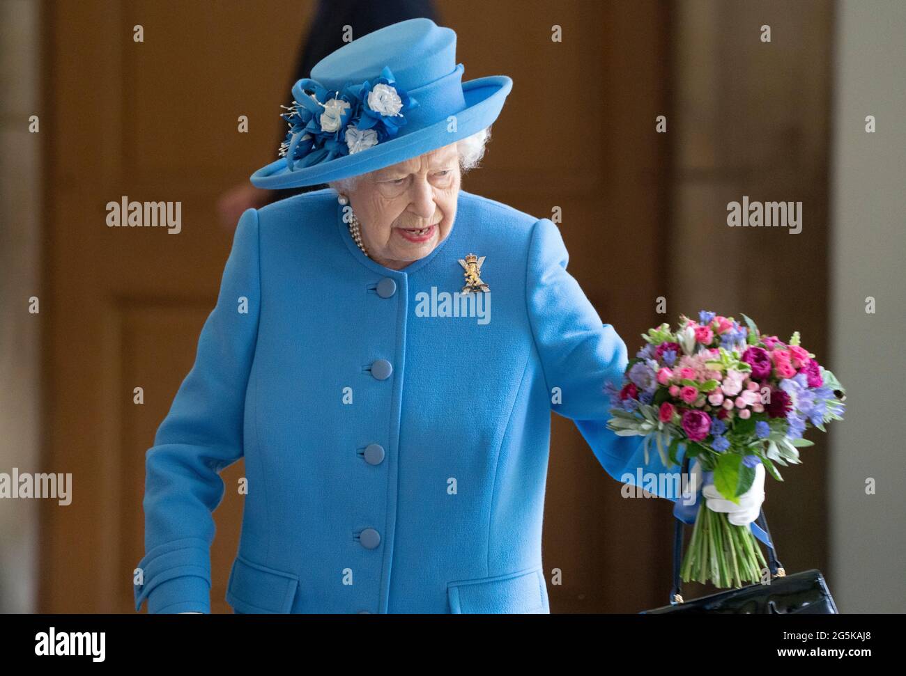 Une abeille atterrit sur les fleurs détenues par la reine Elizabeth II, alors qu'elle rencontra des bénévoles locaux et des travailleurs clés pour les remercier de leurs efforts durant la pandémie, dans la cour du palais de Holyroodhouse à Édimbourg, dans le cadre de son voyage traditionnel en Écosse pour la semaine de Holyrood. Date de la photo: Lundi 28 juin 2021. Banque D'Images