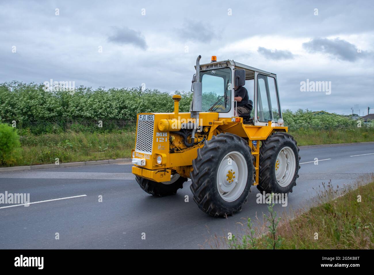 27 juin 2021 - Pocklington, East Yorkshire, Royaume-Uni - Beacon Young Farmers Club Tractor Run. Vieux tracteur jaune sur l'autoroute dans la campagne. Banque D'Images