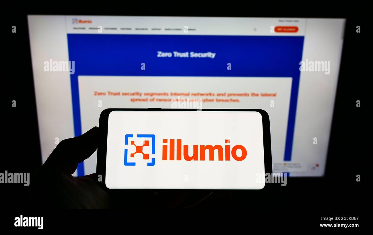 Personne tenant un téléphone portable avec le logo de la société américaine de sécurité de cloud computing Ilumio Inc. À l'écran devant la page Web. Mise au point sur l'affichage du téléphone. Banque D'Images