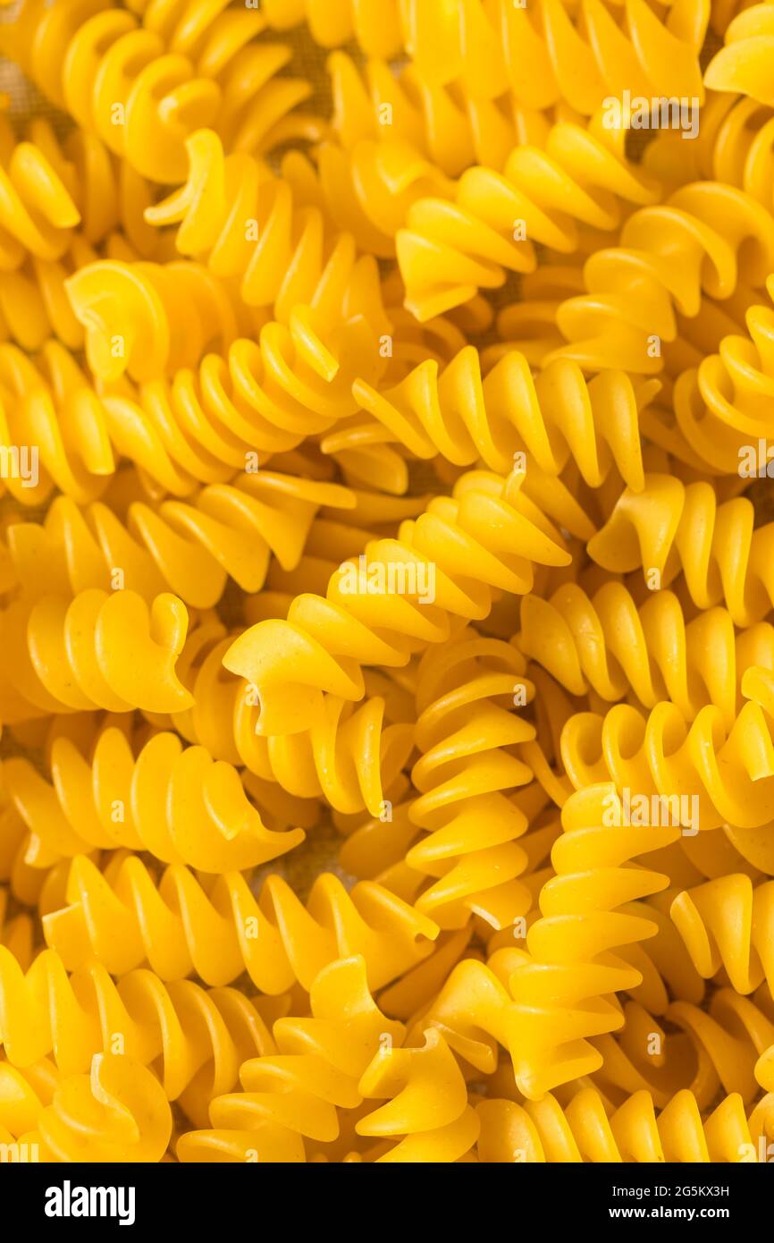 Faites sécher les pâtes à la rotini biologique jaune dans un bol Banque D'Images