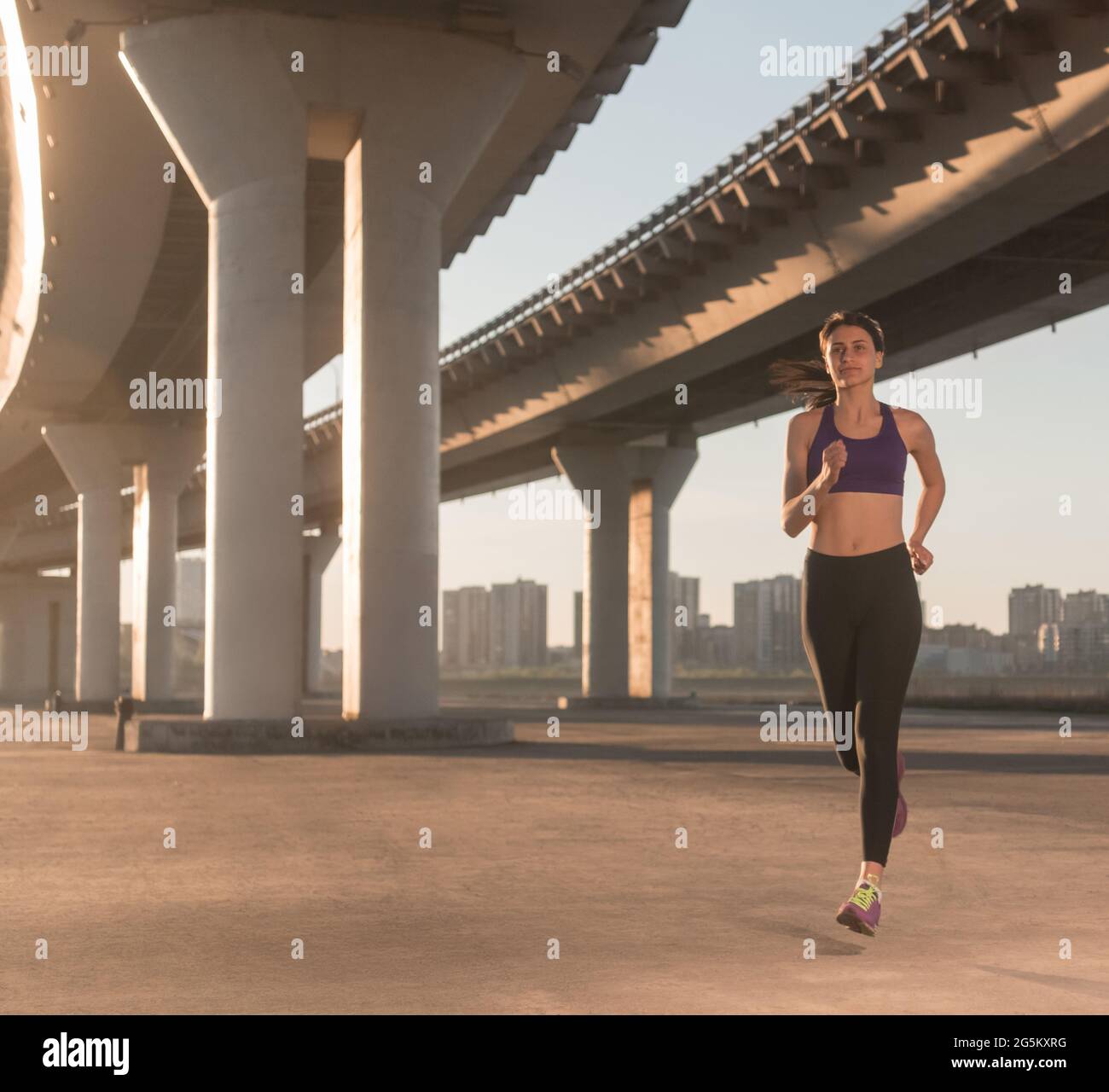 Mettre en place un jogging féminin sous le pont pendant l'entraînement de fitness dans la rue de la ville Banque D'Images