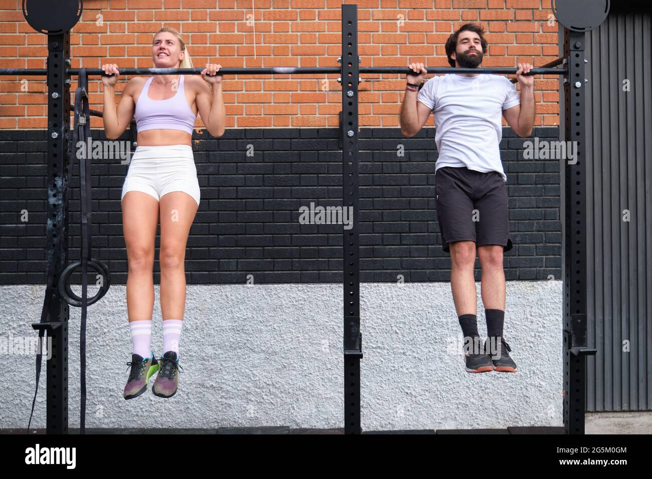 Un jeune homme et une jeune femme qui font des pull-ups à une barre de pull-up crossfit Banque D'Images