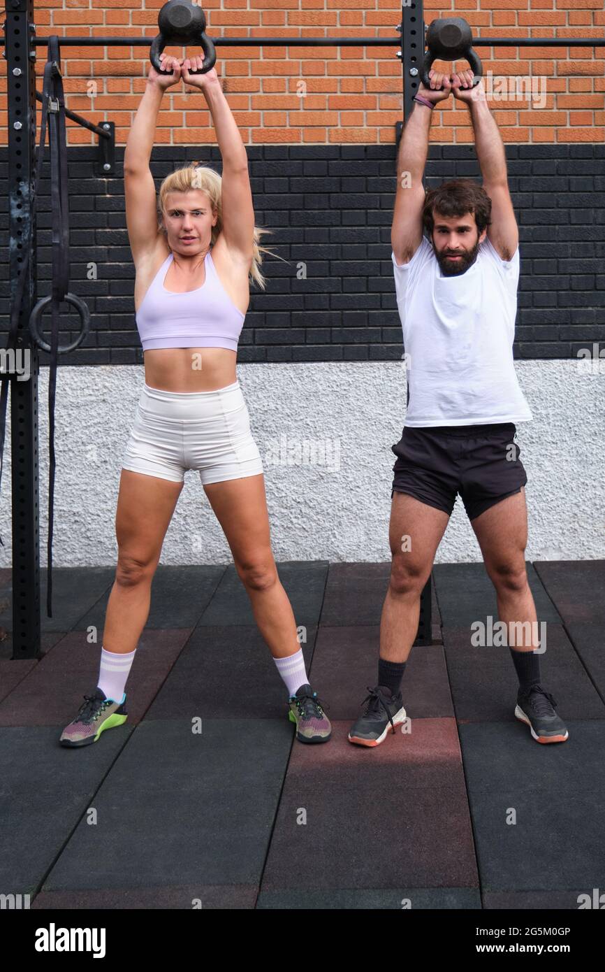 Jeune homme et femme soulevant la kettlebell. Exercices CrossFit. Banque D'Images