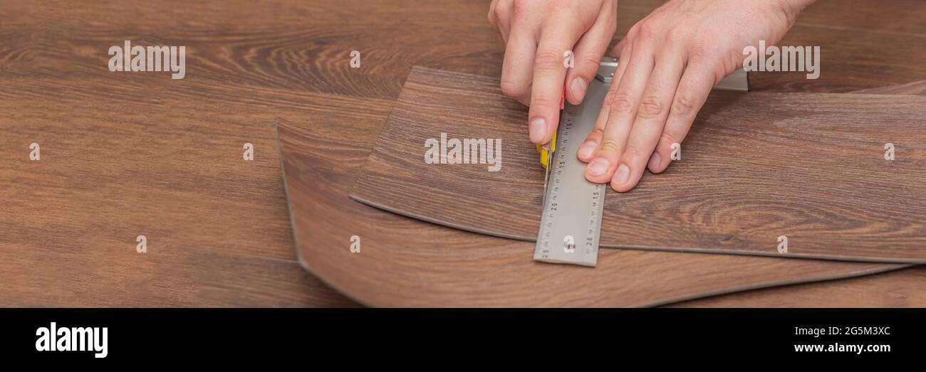 Planchers de vinyle de bricolage. Installation et découpe faciles avec un couteau, Master coupe une planche en vinyle avant l'installation, plancher chauffant marron. Copier l'espace Banque D'Images