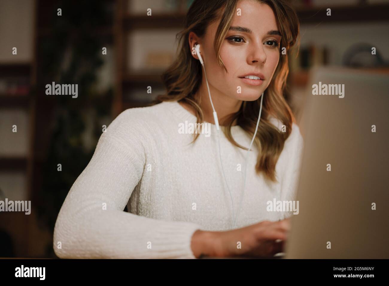 Femme d'affaires sérieuse dans les écouteurs regarder le webinaire sur ordinateur portable prendre des notes, apprendre à étudier l'ordinateur, faire un appel, participer en ligne confe Banque D'Images