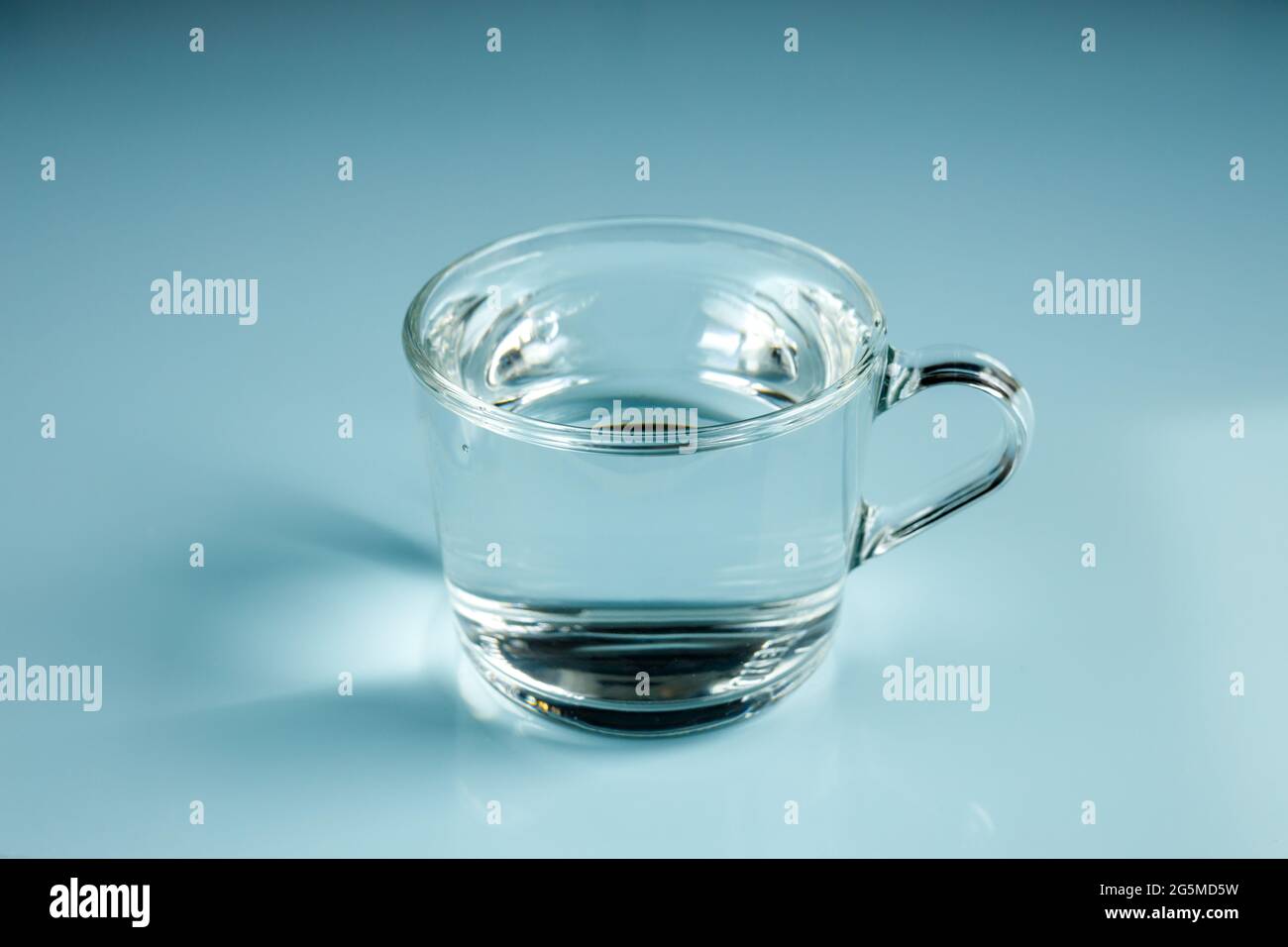 Un verre d'eau claire, disposition minimale, réflexion de lumière, jeu  d'ombre. Fond bleu pastel Photo Stock - Alamy