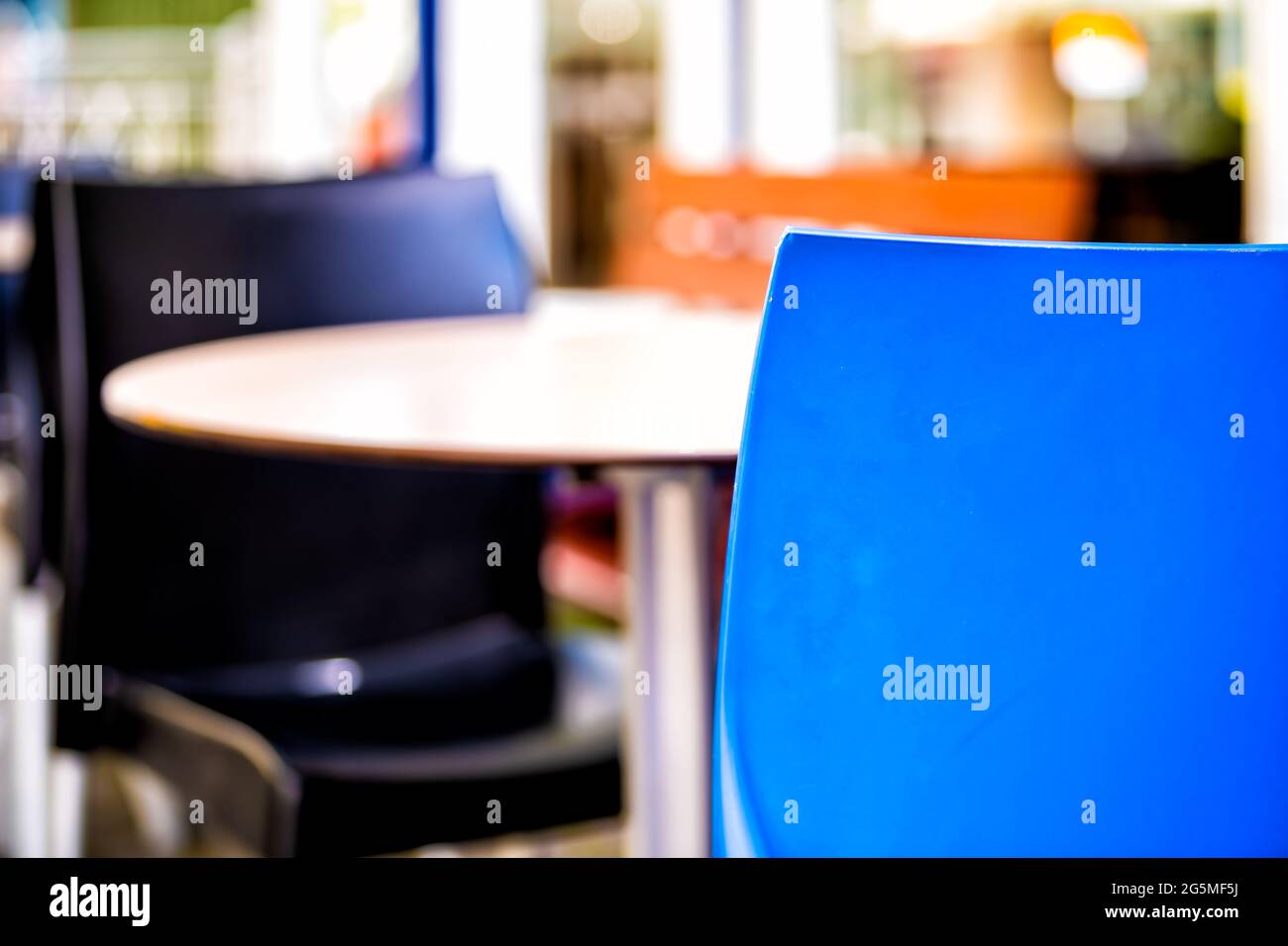 Table vide devant le café du restaurant avec deux chaises bleues colorées sur la rue du trottoir et arrière-plan bokeh avec personne Banque D'Images