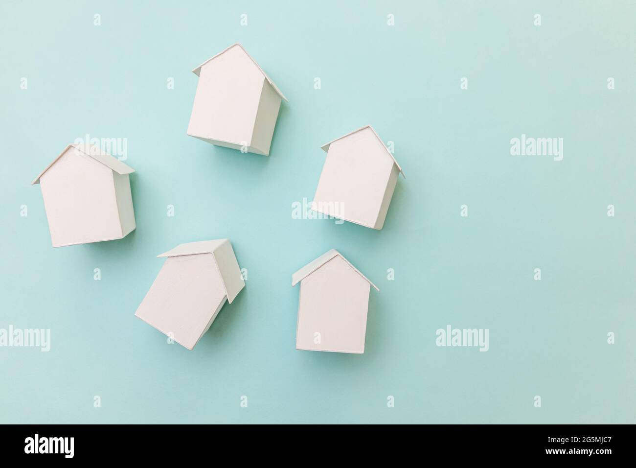 Conception simple et plate avec des maisons miniatures de modèle blanc de jouet isolées sur fond bleu pastel. Assurance de biens immobiliers concept de maison de rêve. Plat Banque D'Images