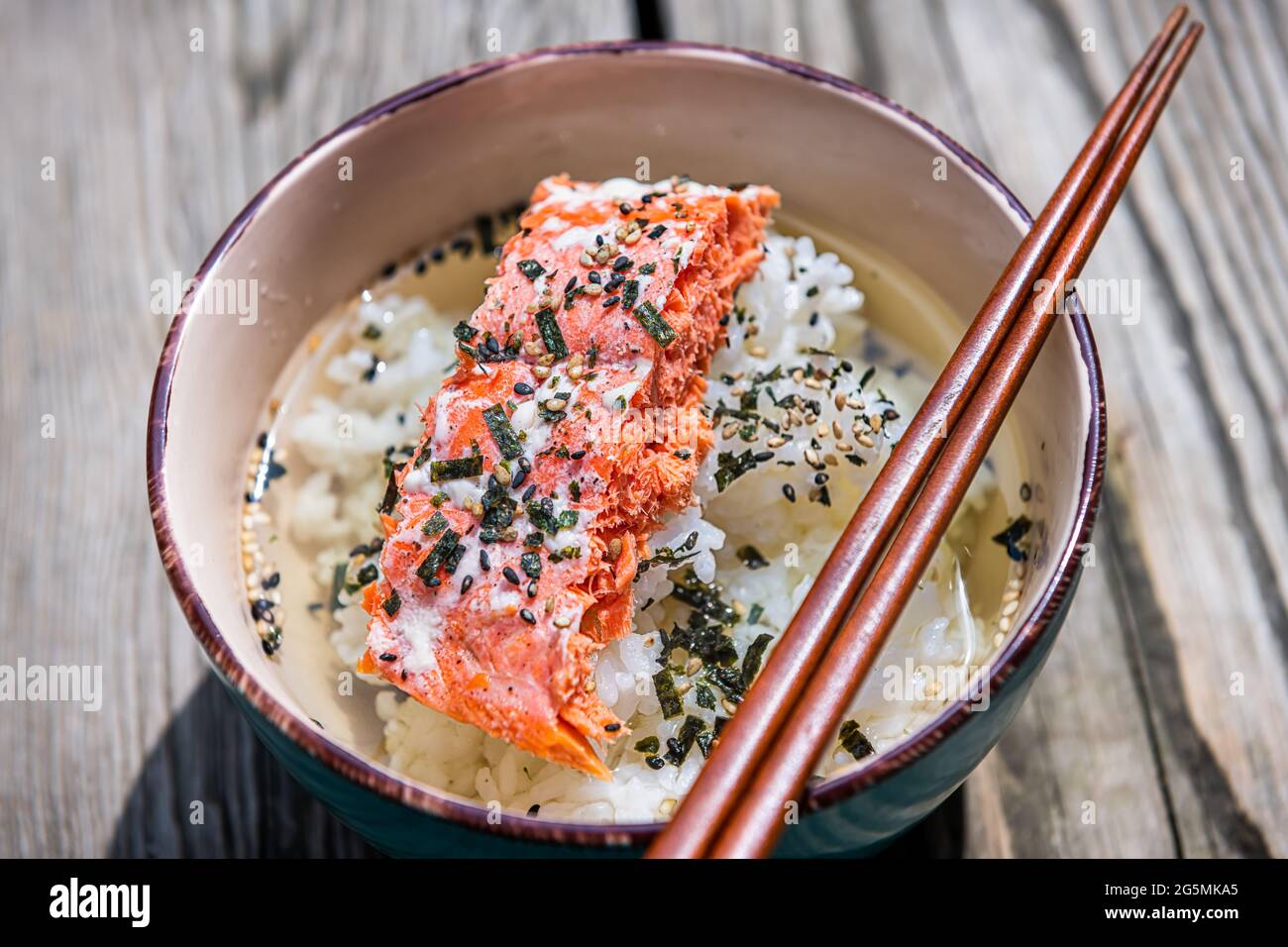 Gros plan du repas traditionnel japonais déjeuner ou dîner plat en Asie appelé ochazuke avec saumon grillé, riz graines de sésame furikake et nori dans un bol avec Banque D'Images