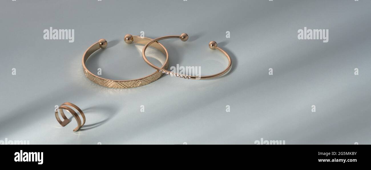 Photo panoramique de bracelets dorés et bague sur fond bleu avec espace de copie Banque D'Images