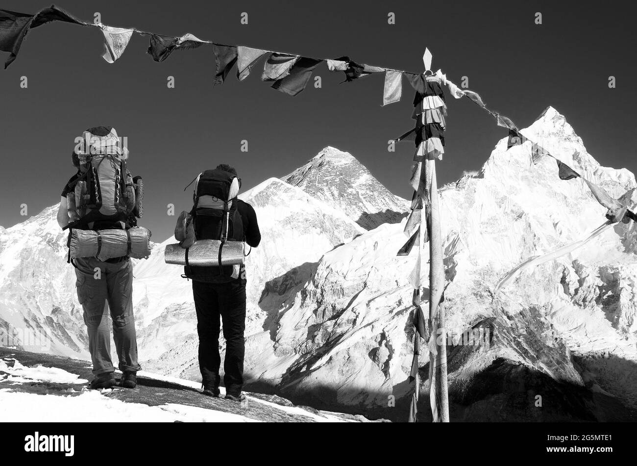 Vue sur l'Everest avec deux touristes et drapeaux bouddhistes de prière de Kala Patthar et le ciel bleu - chemin vers le camp de base de l'Everest, l'himalaya népalais, noir et W Banque D'Images