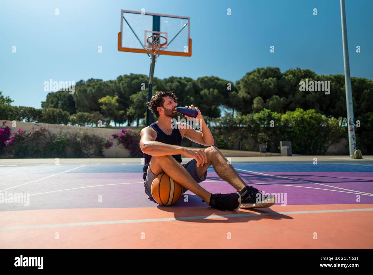 Un homme fatigué, un joueur de basket-ball, boit de l'eau après l'entraînement. Reconstitution de l'équilibre hydrique Banque D'Images