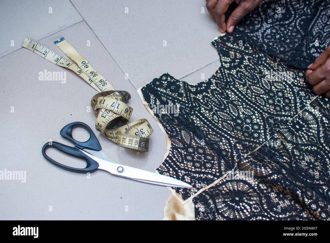 Un dessinateurs de mode africains mains travaillant sur une robe, un tissu ou un clothe avec un mètre ruban et des ciseaux pour obtenir la meilleure sortie comme un tailleur Banque D'Images