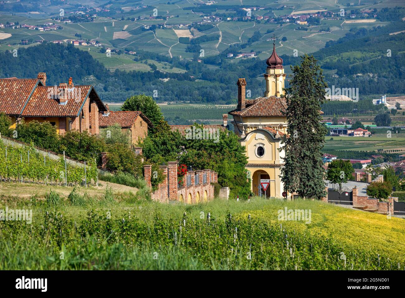 Vue sur le champ vert, les maisons et l'église dans la petite ville de Guarene dans le Piémont, dans le nord de l'Italie. Banque D'Images