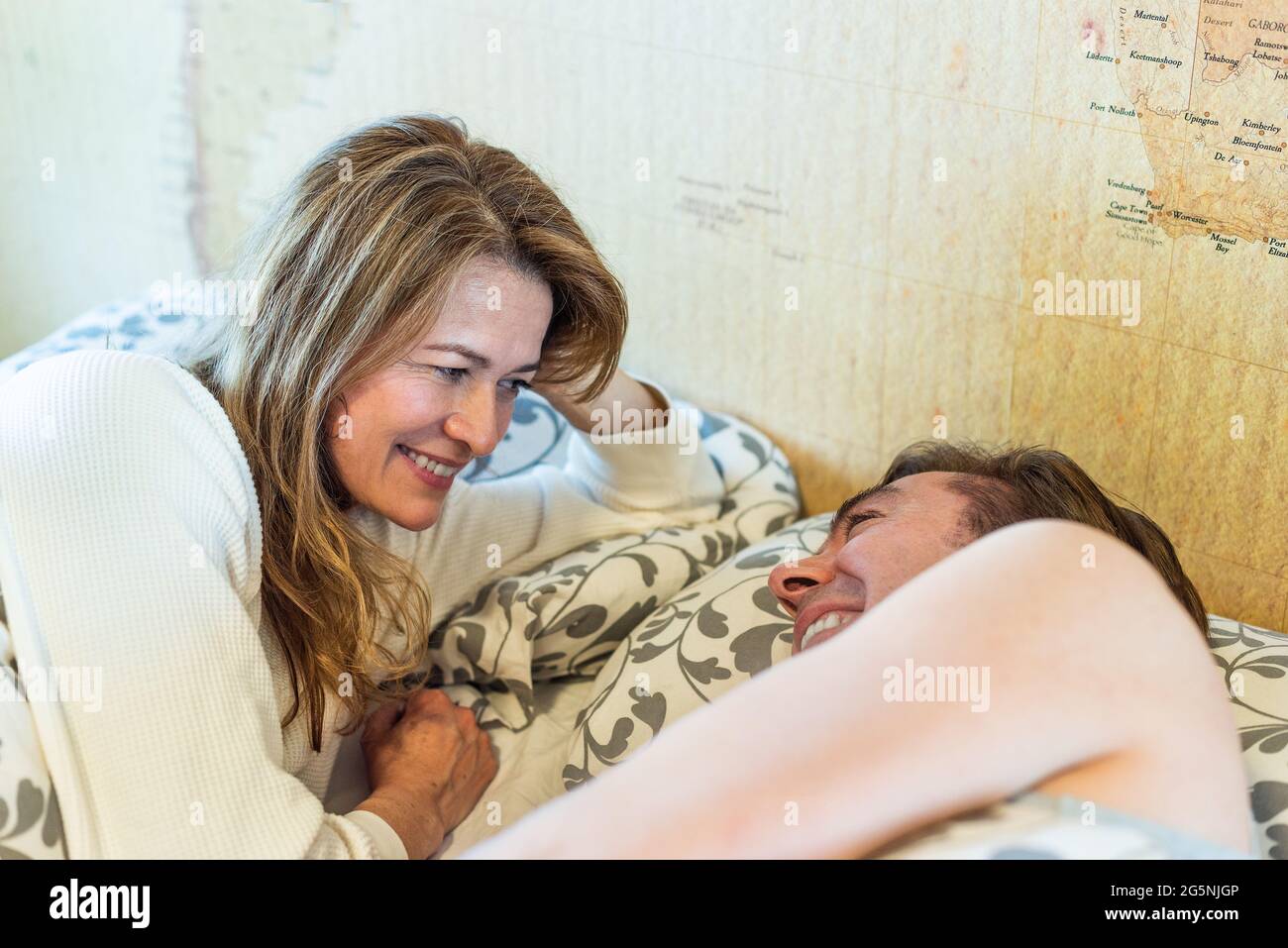 Couple d'âge moyen qui rit allongé sur le lit. Banque D'Images