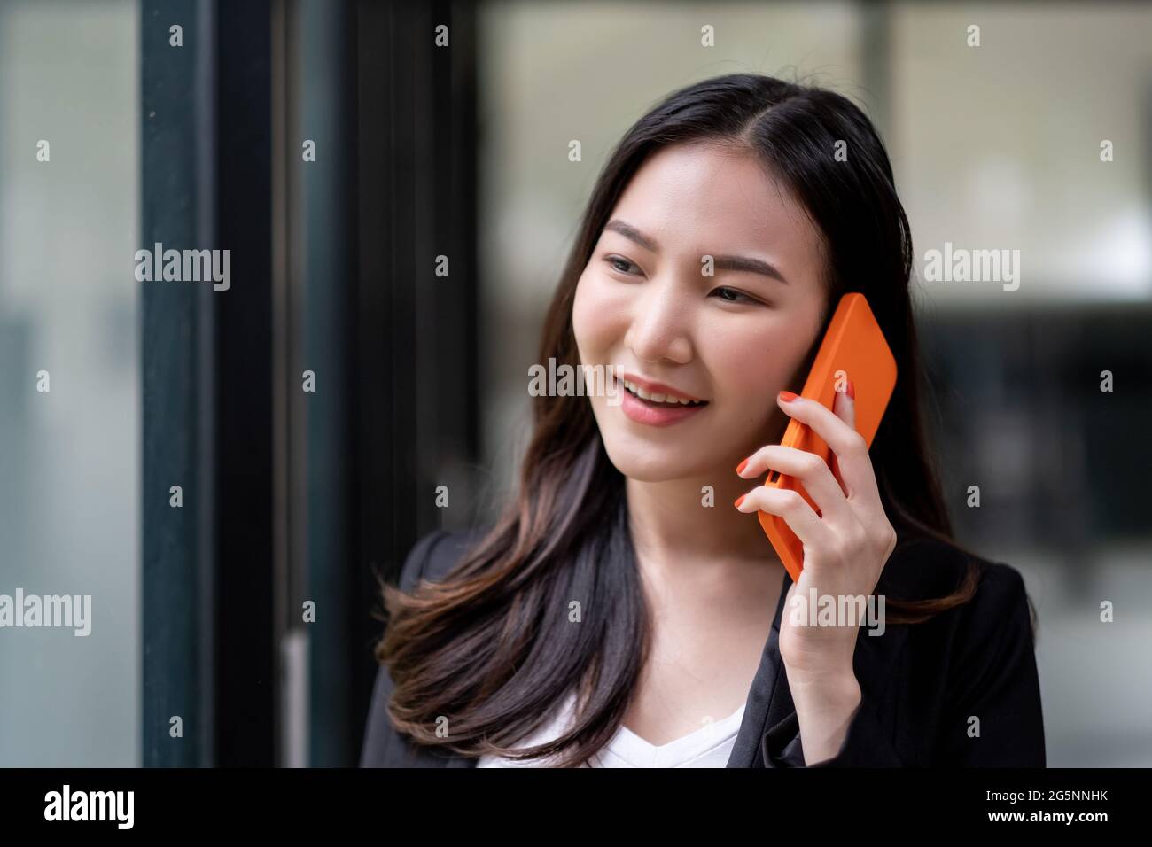 Gros plan femme d'affaires asiatique faisant un appel téléphonique et souriant au bureau Banque D'Images