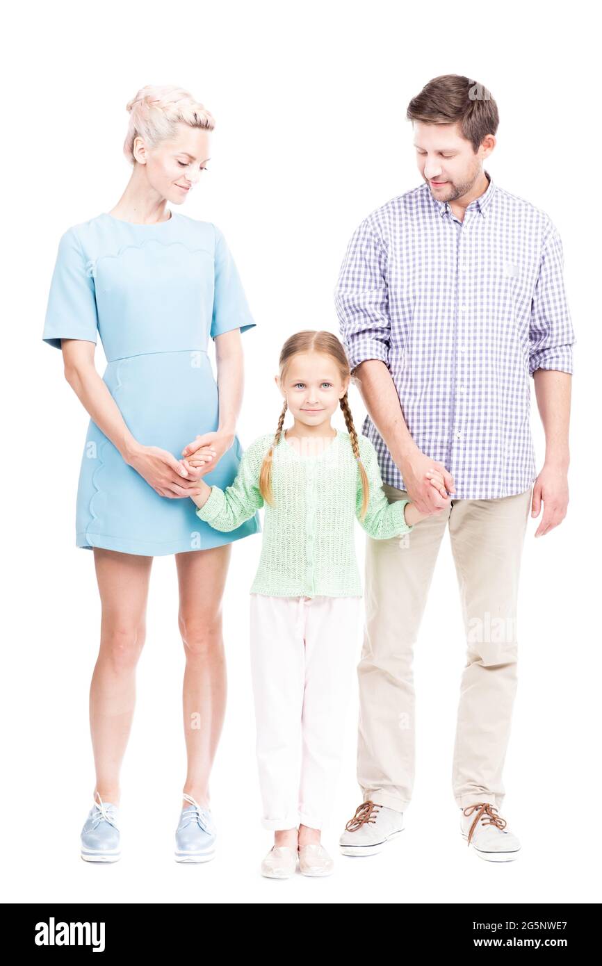 Prise de vue verticale isolée sur toute la longueur de la famille moderne avec une petite fille debout ensemble tenant les mains, fond blanc Banque D'Images
