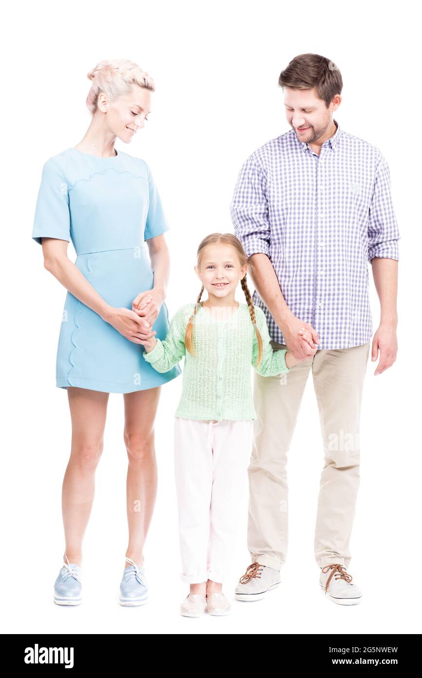 Prise de vue verticale isolée sur toute la longueur de la famille moderne avec une petite fille debout ensemble tenant les mains, fond blanc Banque D'Images