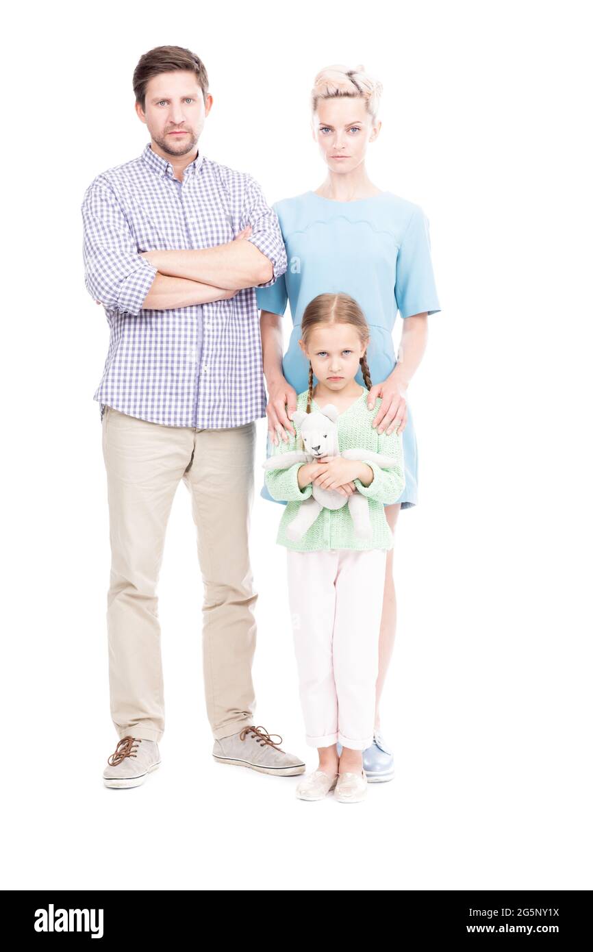 Prise de vue verticale isolée sur toute la longueur de la famille avec un enfant debout ensemble regardant la caméra avec des expressions faciales sérieuses, fond blanc Banque D'Images