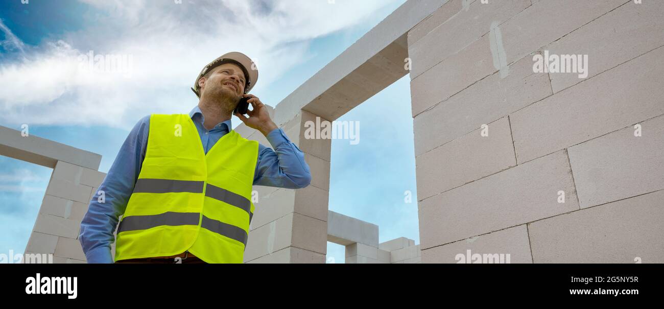 le contremaître de la construction parle sur le téléphone mobile au chantier. bannière de l'espace de copie Banque D'Images