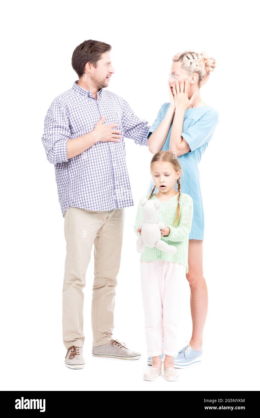 Plan vertical en longueur de l'homme et de la femme moderne debout avec leur petite fille surpris de quelque chose, fond blanc Banque D'Images