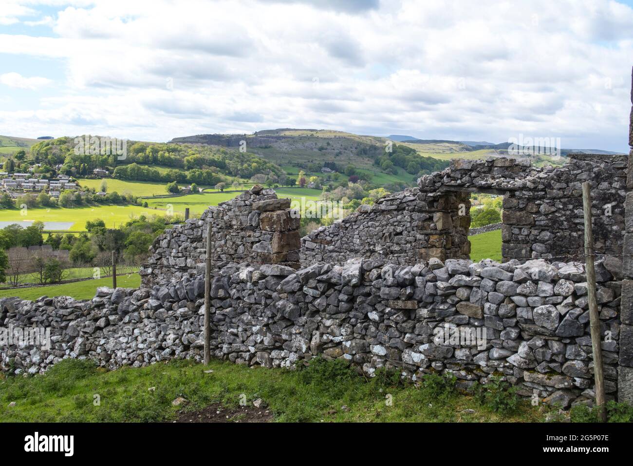 Ancien bâtiment de ferme avec des murs en pierre sèche avec des collines ondoyantes et des champs verts dans la distance de régler les Dales du Yorkshire Banque D'Images