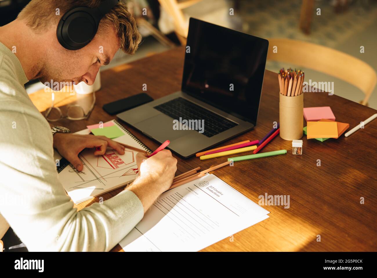 Homme faisant quelques illustrations au bureau à domicile. Un designer masculin prépare des logos pour le client tout en travaillant à domicile. Banque D'Images