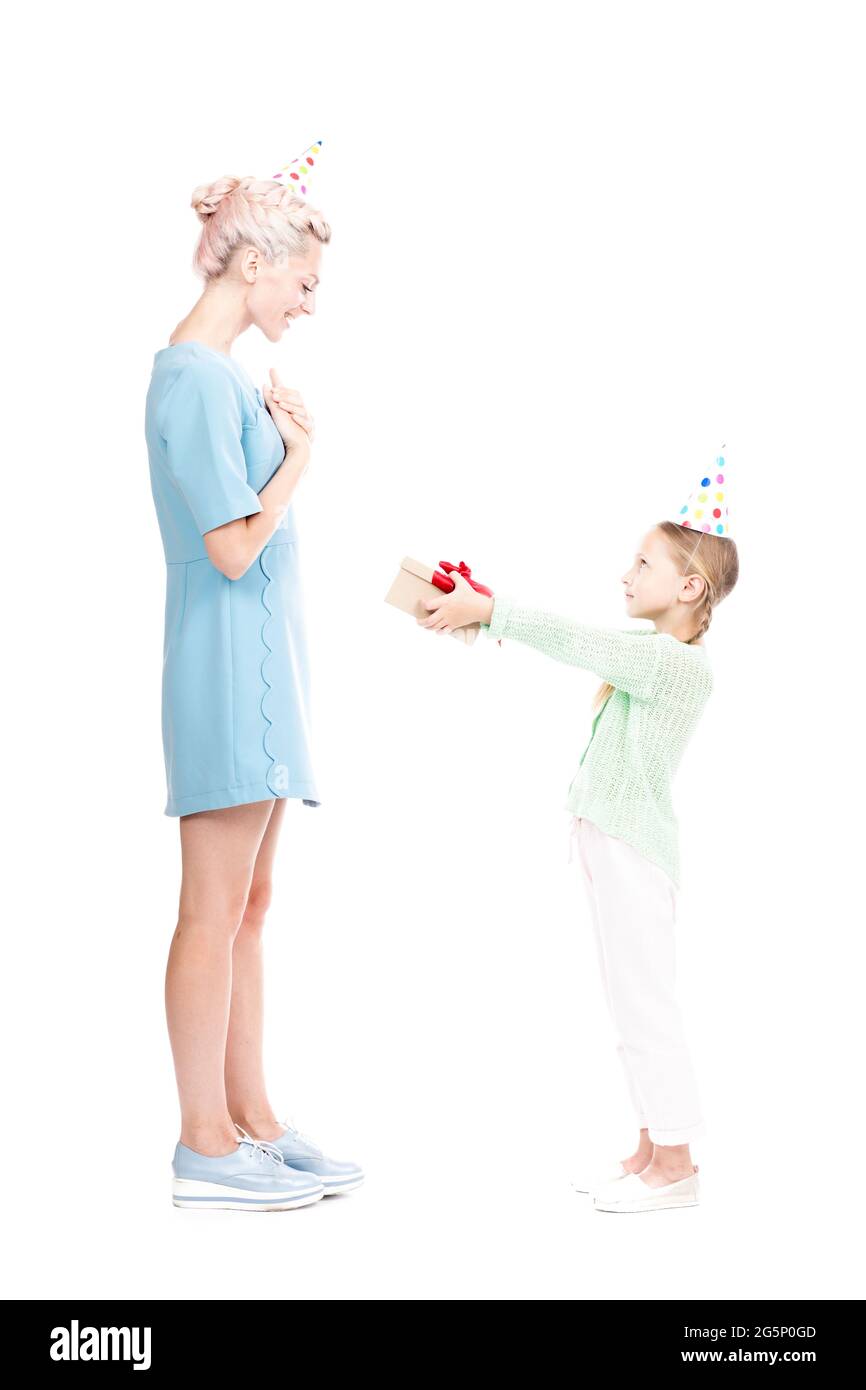 Vue latérale verticale pleine vue de petite fille caucasienne donnant boîte cadeau à sa mère heureuse, fond blanc Banque D'Images