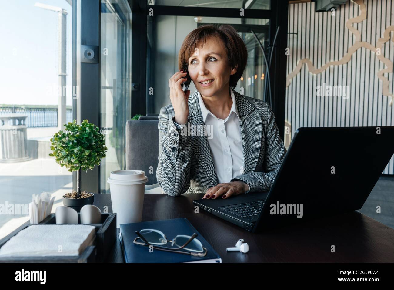 Femme d'affaires senior travaillant dans un café. Travail à distance. Femme parlant sur un téléphone portable. Banque D'Images