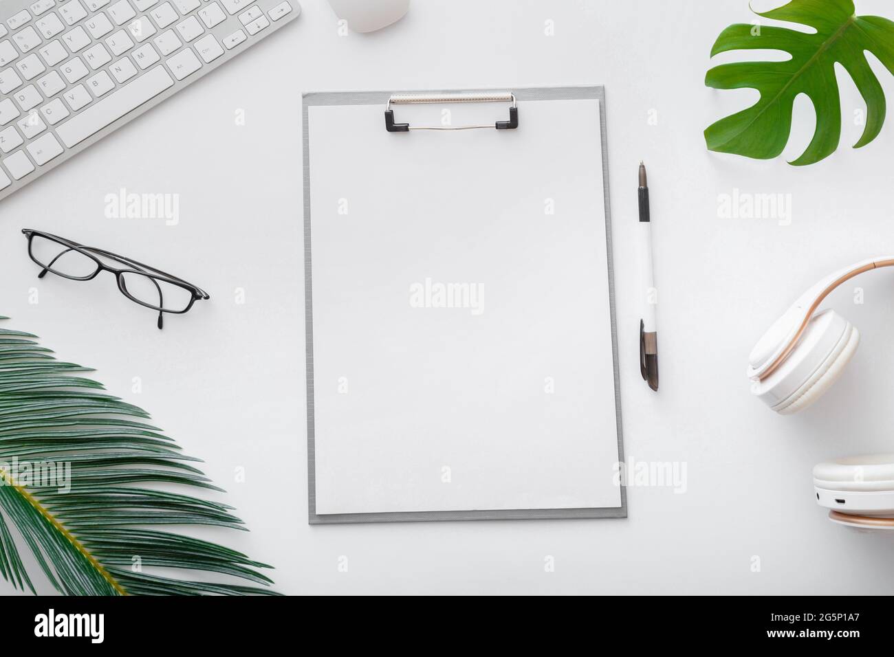 Afficher une liste de notes vide sur l'espace de travail du bureau blanc. Espace de travail indépendant à la maison avec clavier souris lunettes papiers paume feuilles ordinateur portable. Plat Banque D'Images