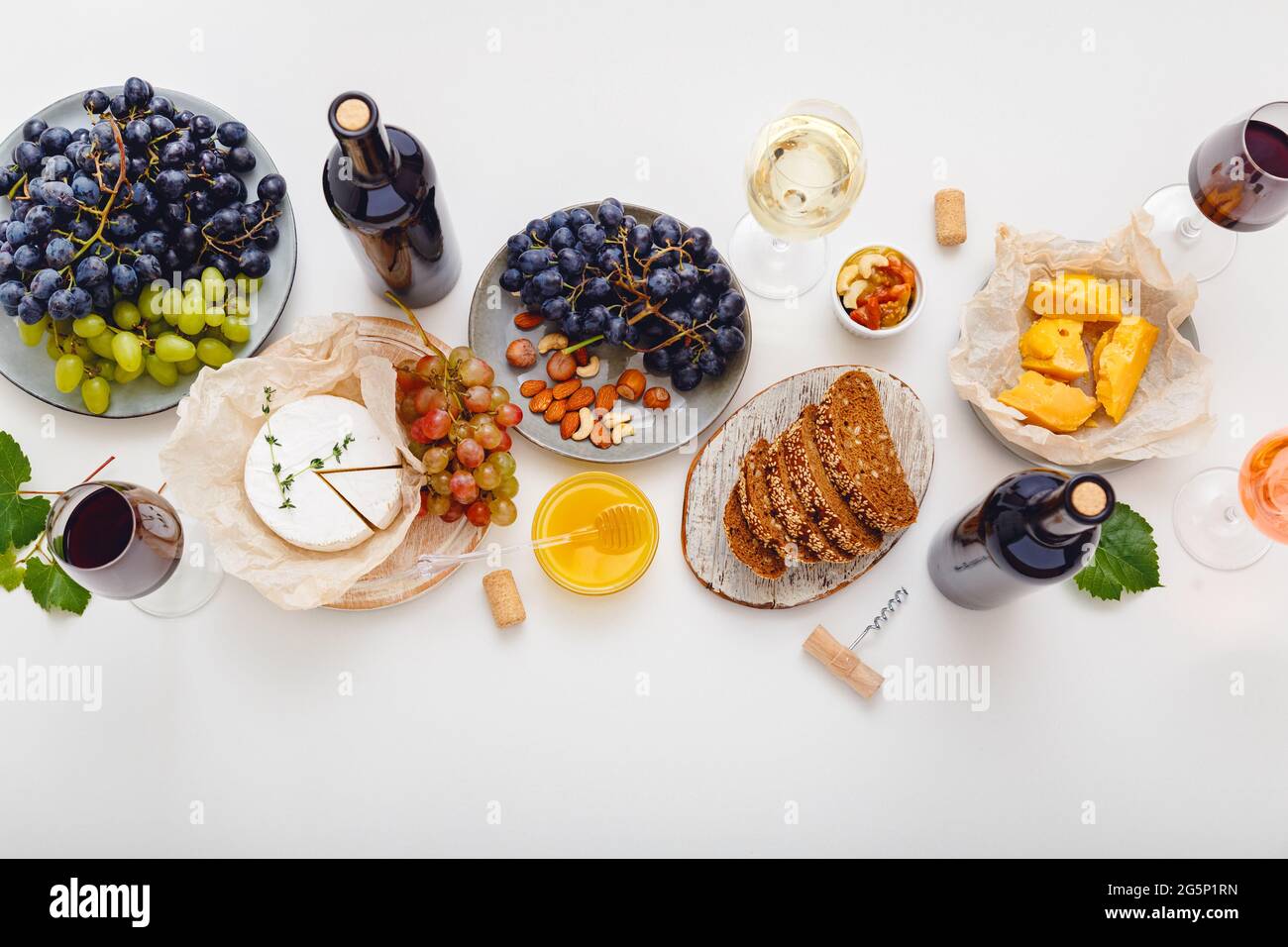 Table de dîner avec vin et raisins de fromage, noix de miel. Table de fête servie avec vin rouge et en-cas méditerranéen sur blanc Banque D'Images