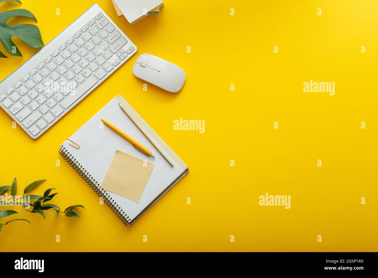 Espace de travail de bureau sur fond jaune vif. Table de bureau aménagement de l'espace de travail avec clavier d'ordinateur, notes de bloc-notes de souris d'usine et copie Banque D'Images