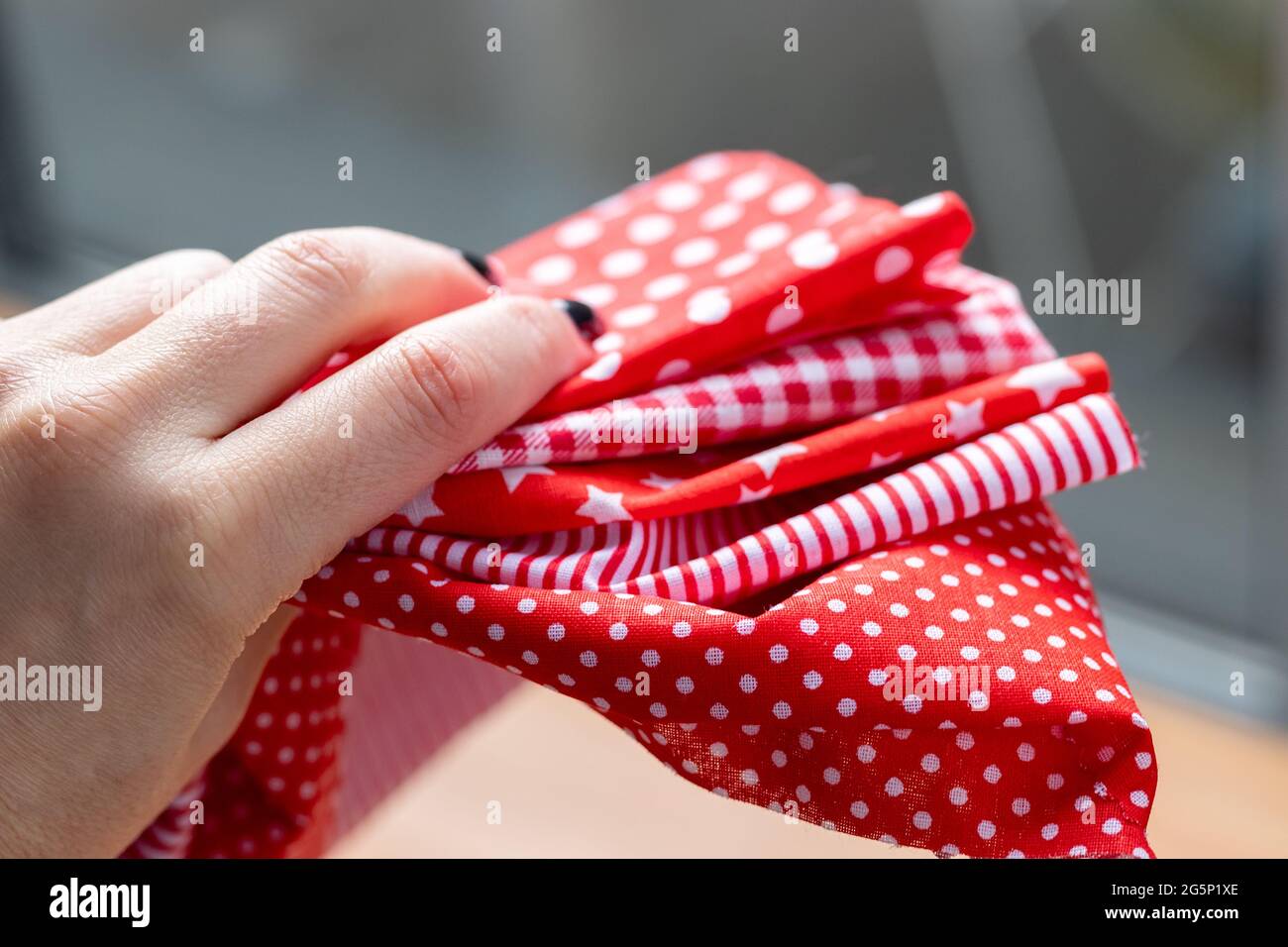 La main féminine tient un tas de cinq types de tissus de coton rouge et blanc avec différents imprimés: À carreaux, rayures, cercle, étoile, pois. Sélectif f Banque D'Images