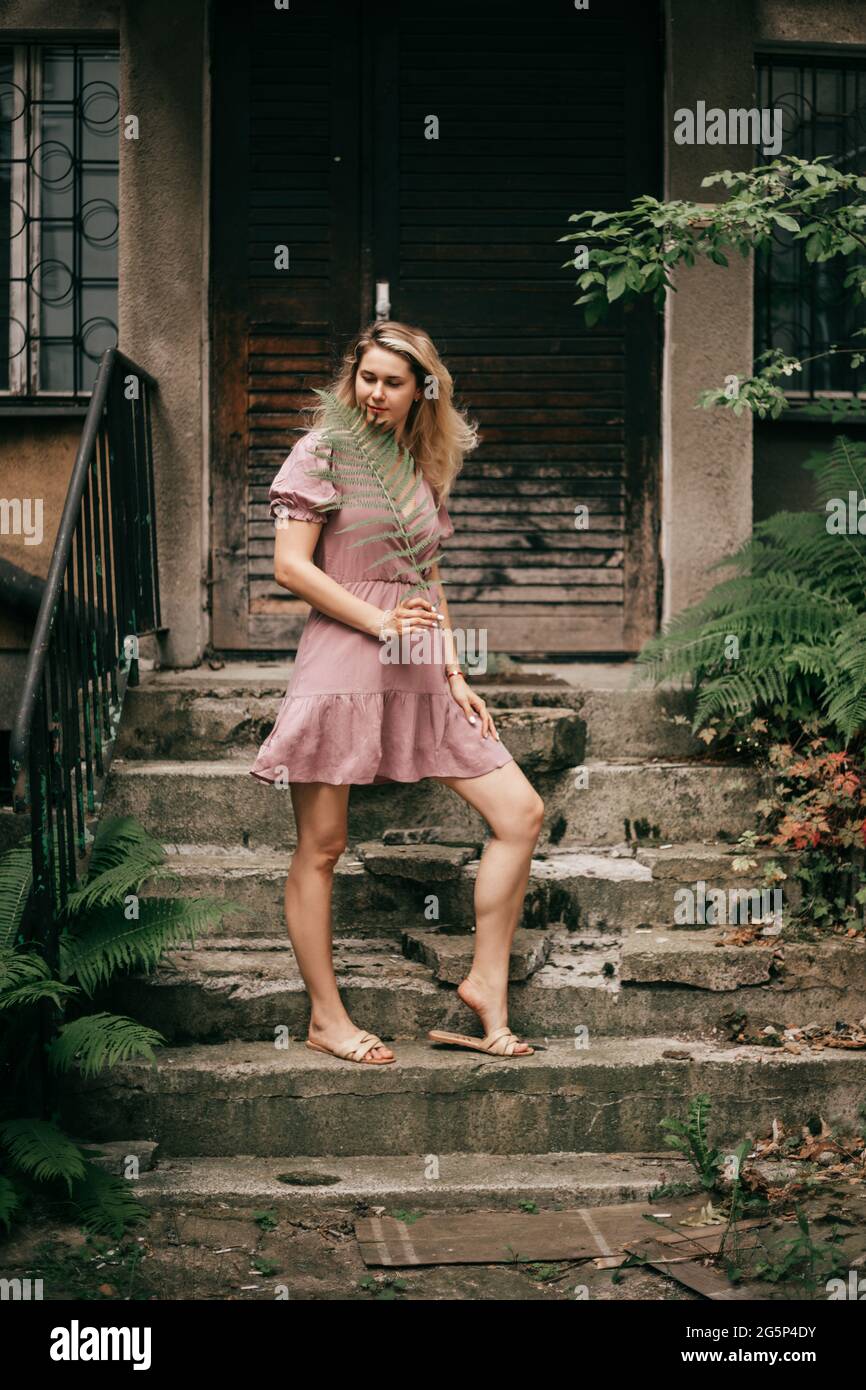 Une jeune fille mince en robe courte en tissu naturel est debout sur des  marches de maison authentique avec la fougère dans les mains Photo Stock -  Alamy