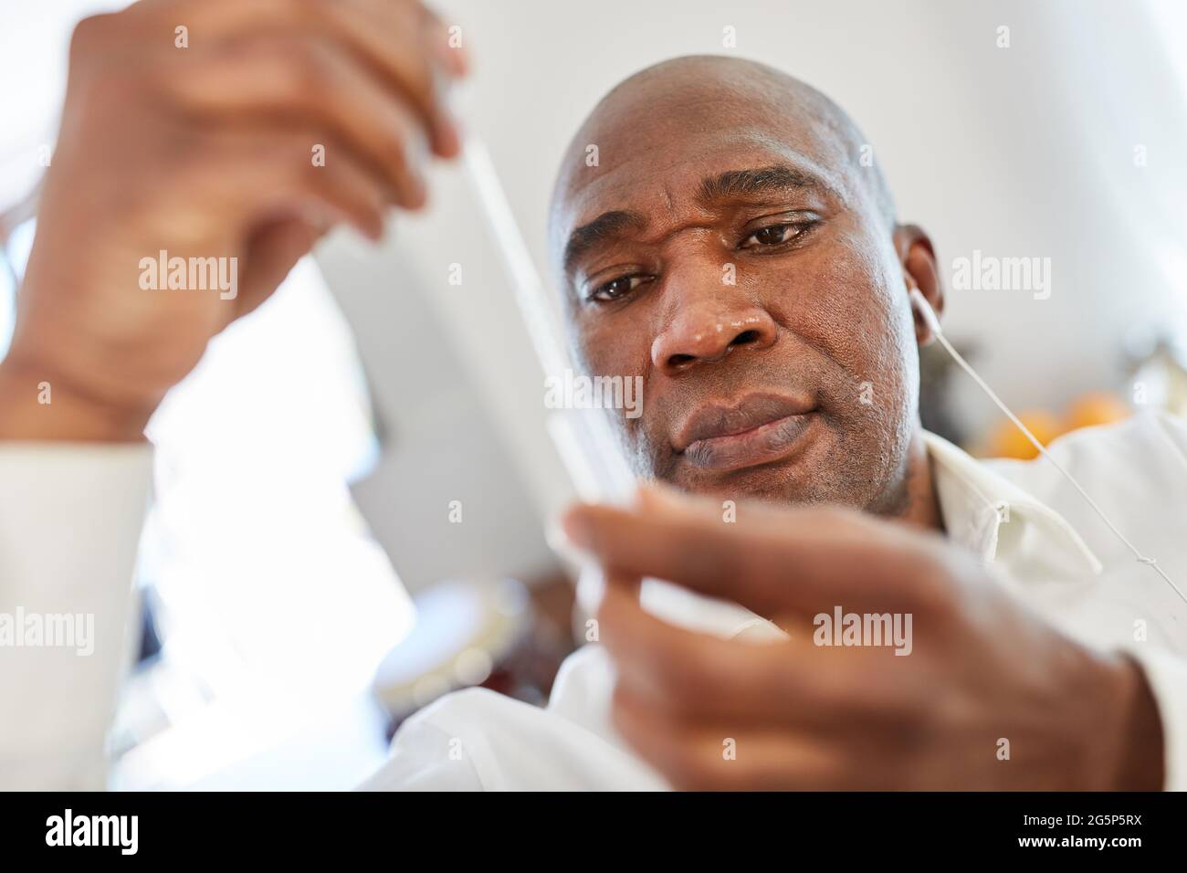 Homme afro-américain effectuant un test d'antigène rapide Covid-19 avec un échantillon de salive à la maison Banque D'Images