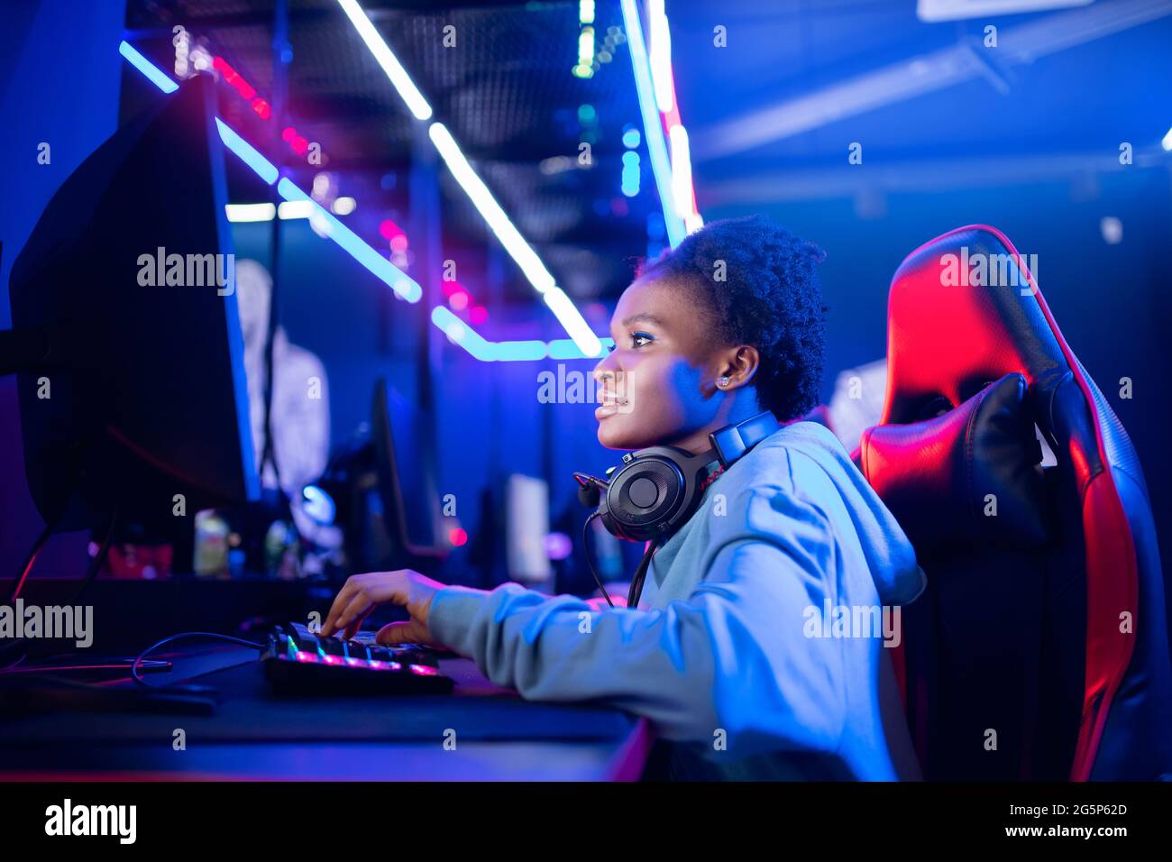 Portrait Gamer African American belle femme jouer en ligne jeux ordinateur, streamer néon salle. Banque D'Images