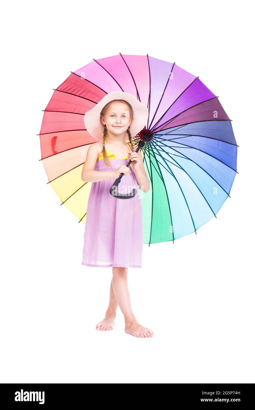 Portrait de studio vertical de petite fille caucasienne portant une robe d'été et un chapeau tenant un parapluie coloré posé sur l'appareil photo, fond blanc Banque D'Images