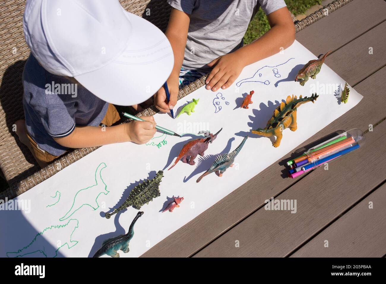 Deux enfants d'âge préscolaire méconnaissables dessinent des ombres contrastées des dinosaures à l'aide d'un stylo feutre. Des idées créatives pour la créativité des enfants. Intéressant a Banque D'Images