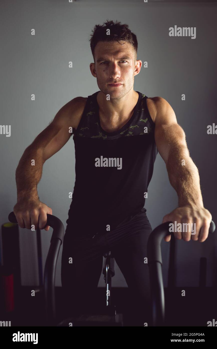 Portrait de la forme homme caucasien s'exerçant à la salle de gym, sur le vélo d'exercice Banque D'Images