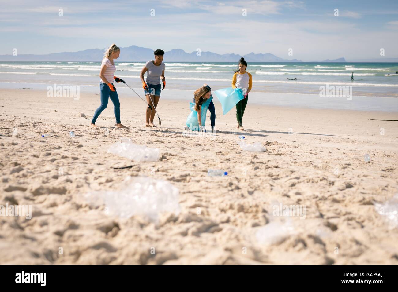 Divers groupes de femmes marchant le long de la plage, ramassant des ordures Banque D'Images