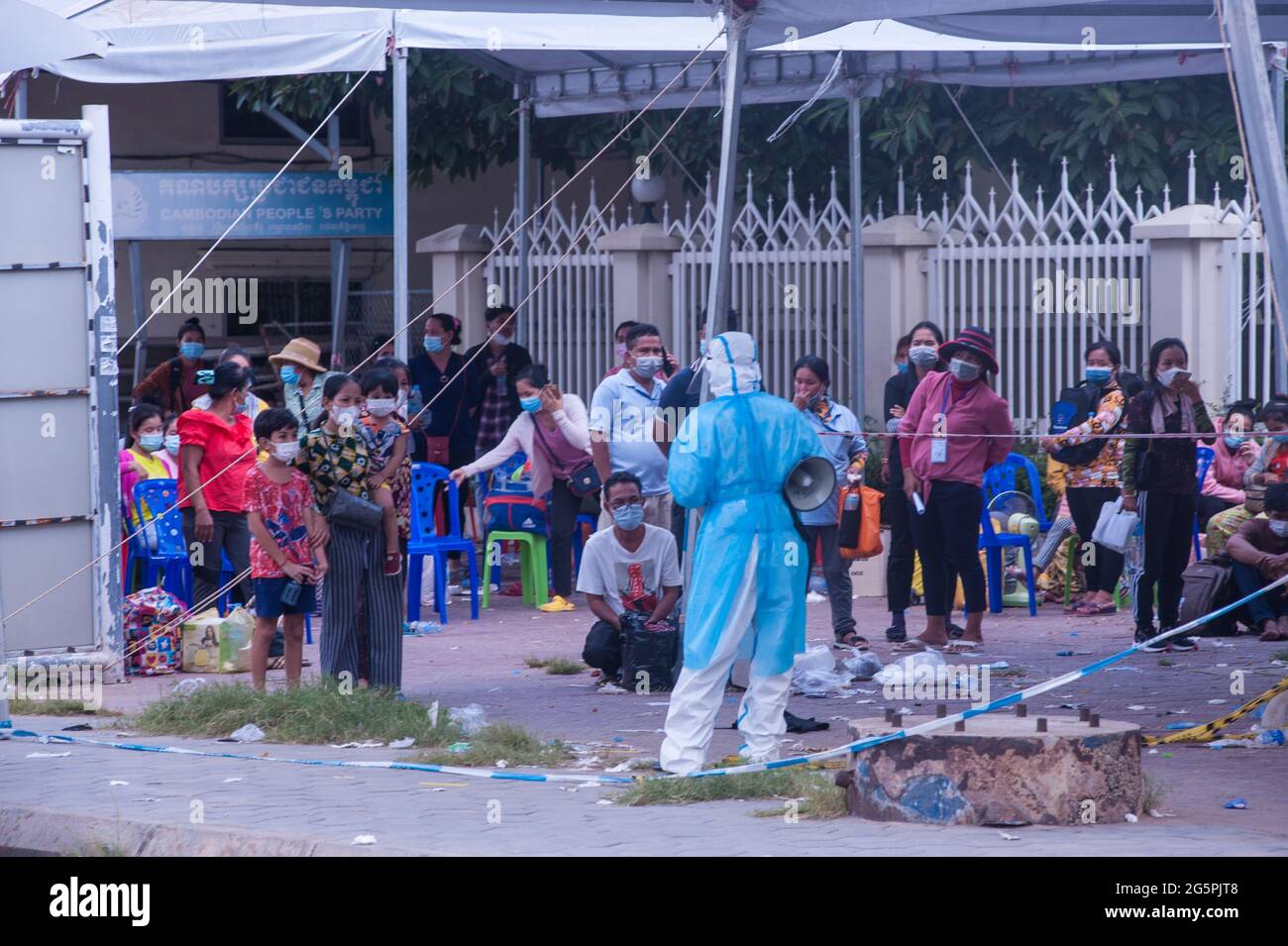 Phnom Penh, Cambodge. Le 29 juin 2021. Depuis 4 mois, Phnom Penh lutte contre une vague de COVID - 19. Un EMT dans l'EPI complet dirige un site de tests de masse. Une mère cambodgienne et ses deux petits garçons ont tous été testés positifs pour le virus et sont ramassés par une ambulance. Credit: Kraig Lieb / Alamy Live News Banque D'Images