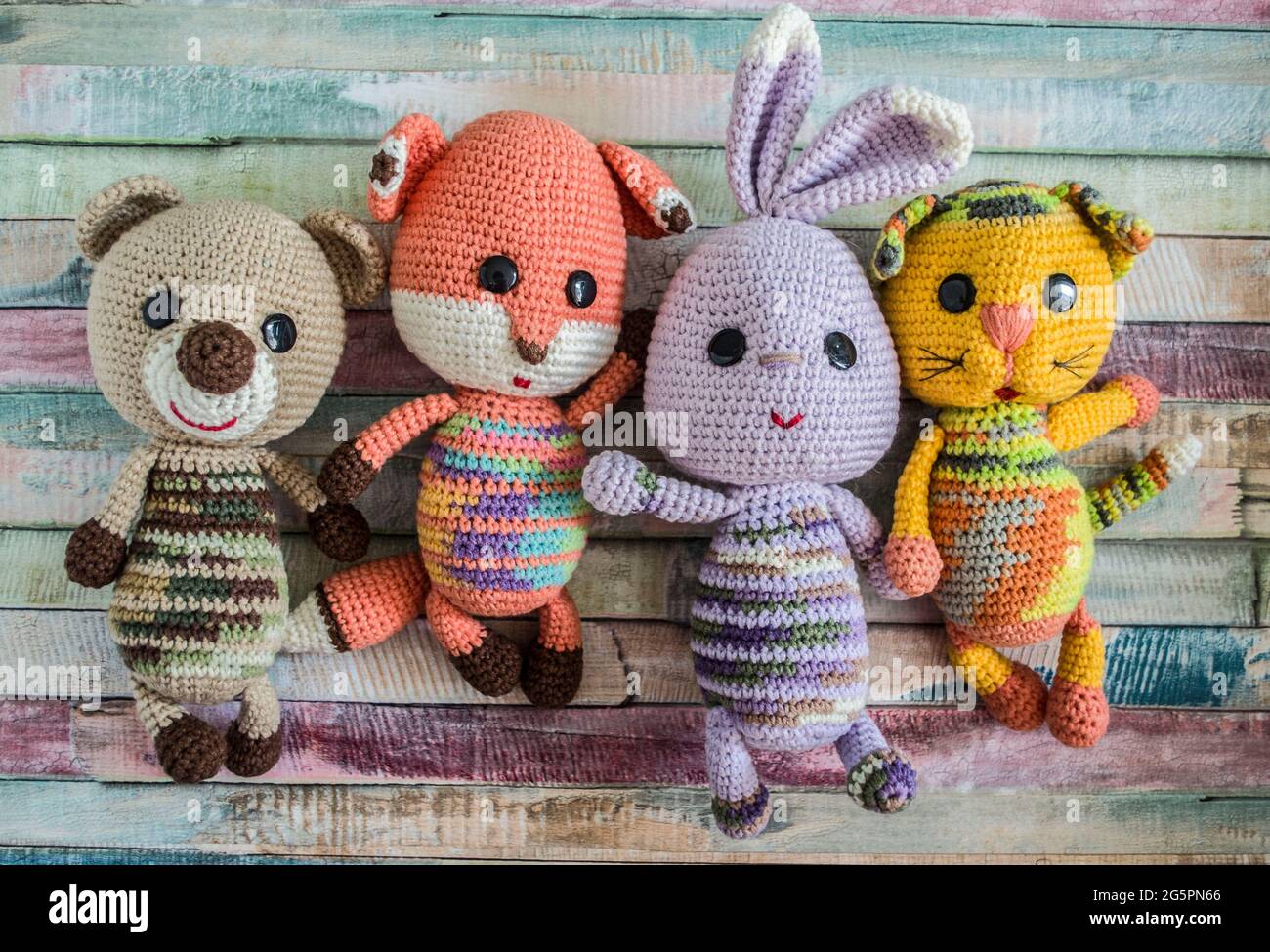 Ours en peluche crocheté lièvre chat et chanterelle sur fond de bois. Jouets faits main. Banque D'Images