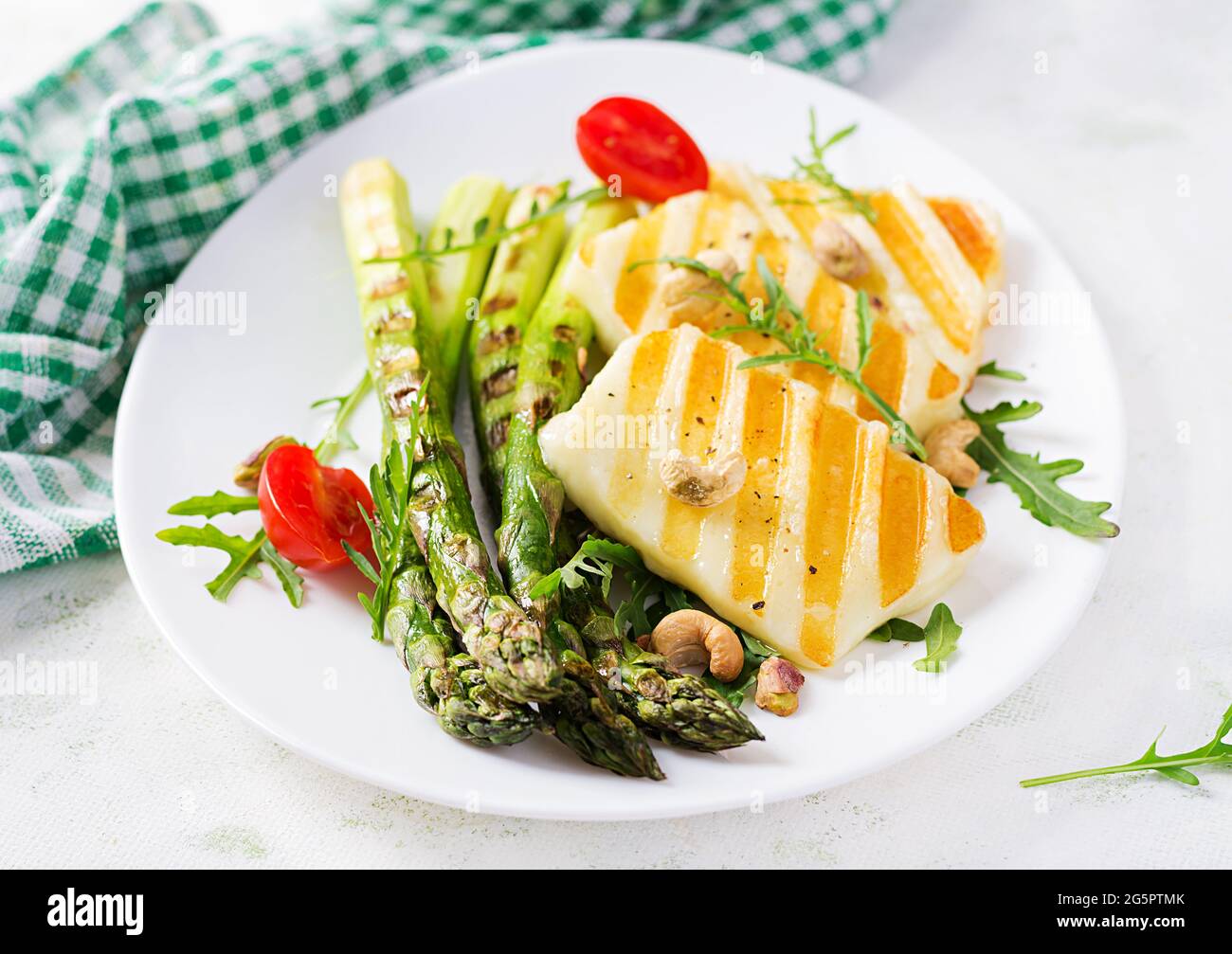 Salade de fromage halloumi grillé avec tomates et asperges sur plaque sur fond clair. Nourriture végétarienne saine. Banque D'Images