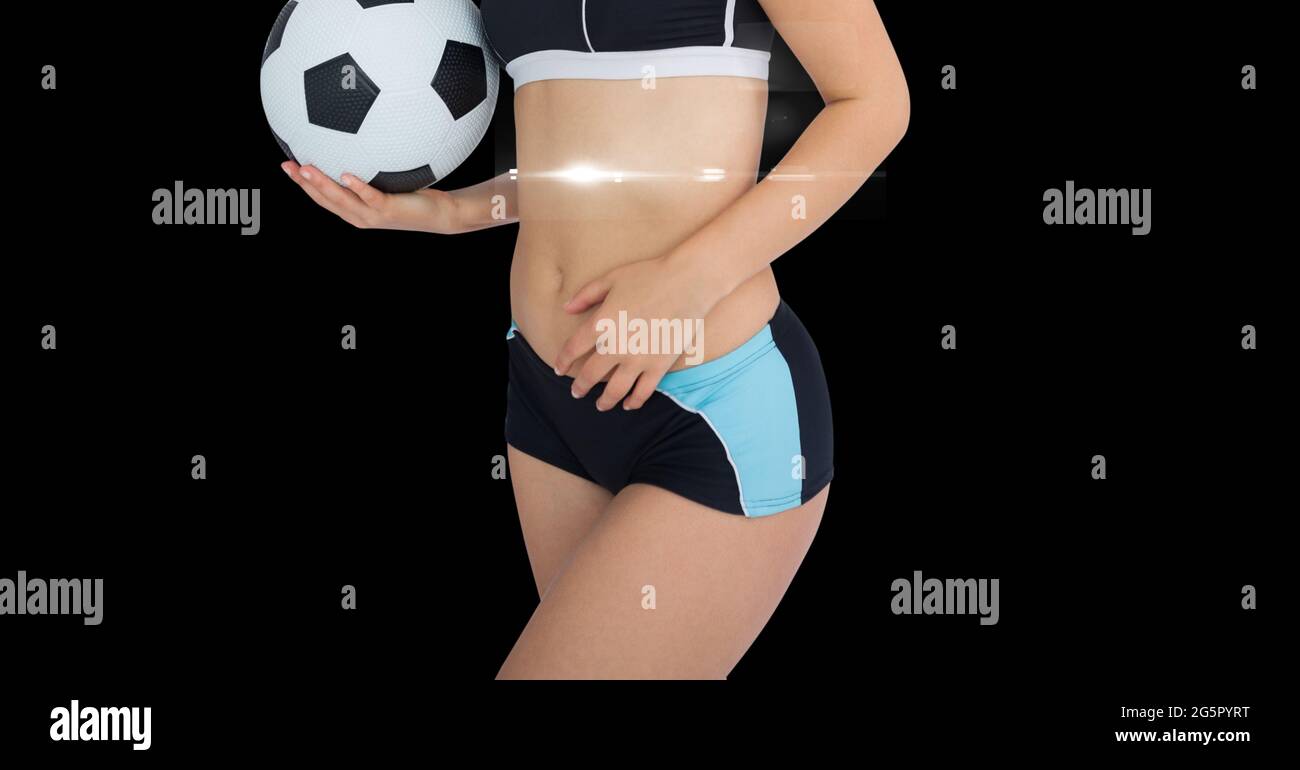 Section médiane d'une athlète féminine portant un ballon de football sur fond noir Banque D'Images