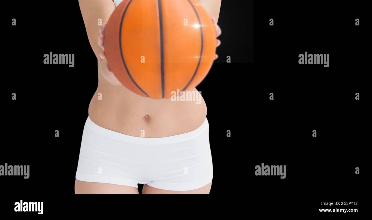 Section médiane d'une athlète féminine portant un ballon de basket-ball sur fond noir Banque D'Images