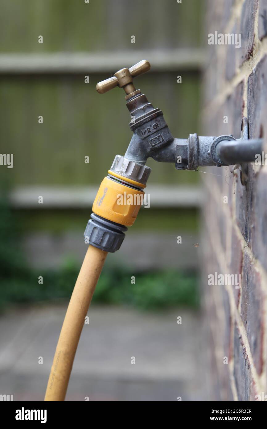 Ancien style de robinet d'eau extérieur sur mur en brique avec fixation de  tuyau de hozelock et tuyau d'arrosage au jardin d'eau, été 2021 Photo Stock  - Alamy