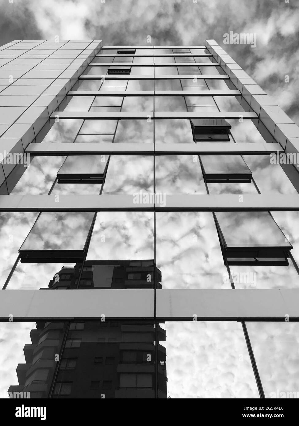 Photo d'un immeuble de bureaux et de sa réflexion par temps froid et nuageux, avec un filtre monochrome noir et blanc. Banque D'Images
