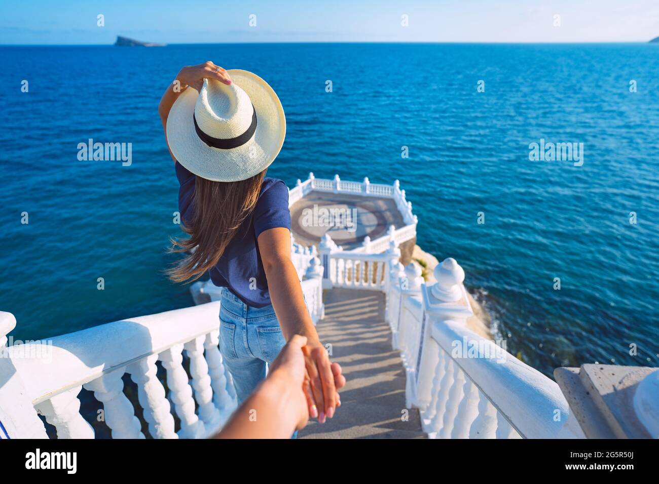 Femme touristique insouciante en chapeau menant son petit ami à la vue sur la mer. Suivez-moi. Balcon del Mediterraneo, Benidorm, Espagne Banque D'Images